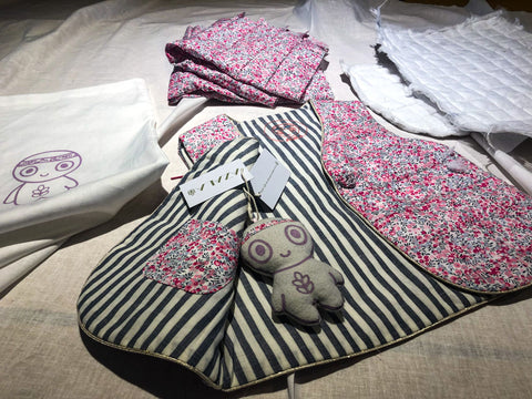 Gilet Azala exposé avec tout ses composants: mascotte Azala (upcycling), Etiquettes Azala (recyclées), Pochon Azala (Upcyclé), matelassage Azala (100% recyclé).